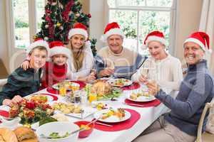 Smiling family in santa hat toasting to camera