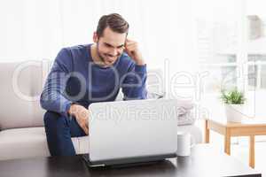 Smiling young man using his laptop