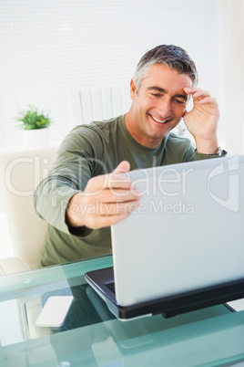 Cheerful man sitting and holding his laptop