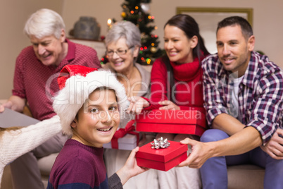 Smiling son exchanging gift with his family behind