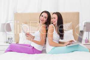Pretty friends using their technology on bed