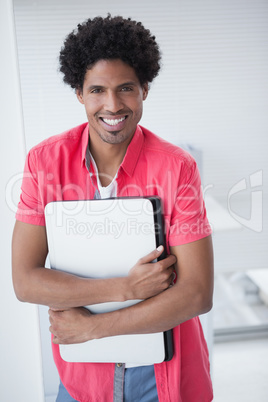 Smiling casual businessman holding laptop