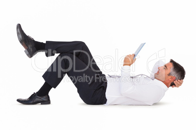 Peaceful businessman lying and using tablet pc