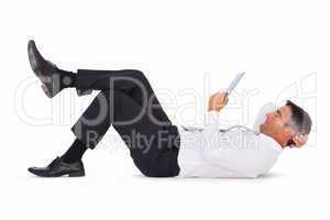 Peaceful businessman lying and using tablet pc