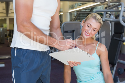 Woman discussing her performance on clipboard with a trainer at