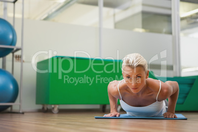 Beautiful woman doing push ups in in fitness studio