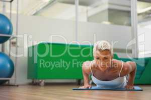 Beautiful woman doing push ups in in fitness studio