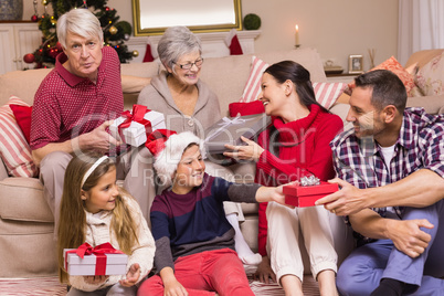 Multi generation family exchanging presents on couch