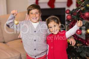 Happy brother and sister holding baubles