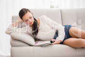 Pretty brunette reading magazine on the couch