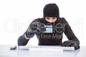 Burglar doing online shopping with laptop and credit card