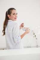 Pretty brunette eating bowl of cereal