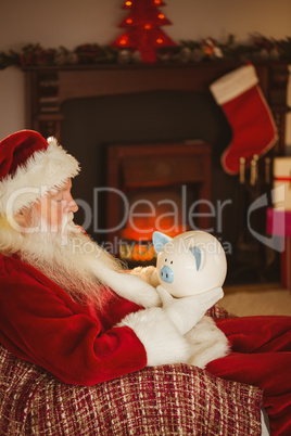 Santa claus holding piggy bank at christmas