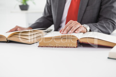 Businessman sitting at desk reading books