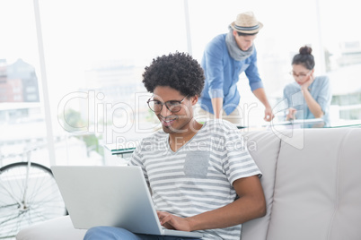 Young creative man using laptop on couch