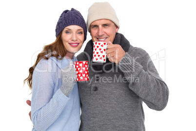 Happy couple in warm clothing holding mugs