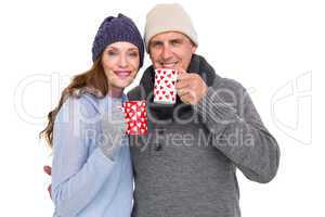 Happy couple in warm clothing holding mugs