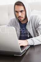 Serious young man using his laptop