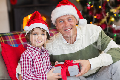 Son offering father a christmas gift on the couch