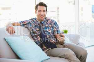 Happy man sitting on the couch sending a text message
