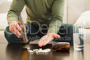 Man showing pills and holding beer bottle