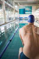 Rear view of shirtless swimmer by pool at leisure center