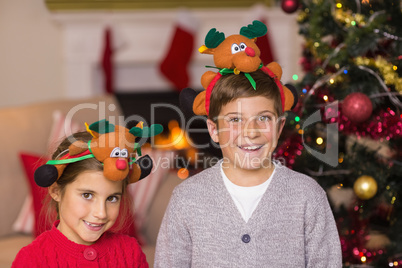 Happy brother and sister in headband near christmas tree