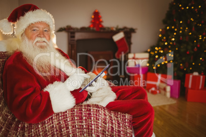 Happy santa touching tablet on the couch