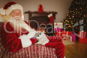 Happy santa touching tablet on the couch