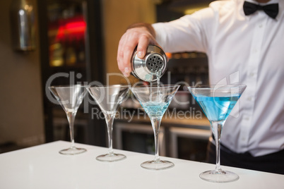 Bartender pouring blue alcohol into cocktail glass