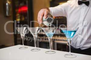 Bartender pouring blue alcohol into cocktail glass