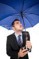 Focused businessman under umbrella looking up