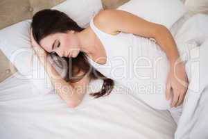 Pregnant brunette sleeping in bed