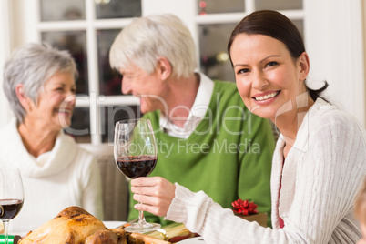 Portrait of woman toasting at camera during christmas dinner