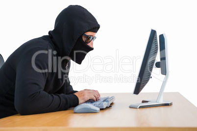 Burglar with sunglasses typing on keyboard