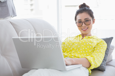 Young creative woman using laptop on couch