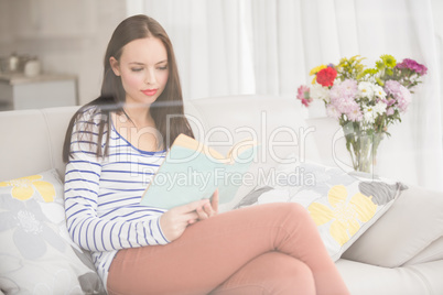 Pretty brunette reading book on couch