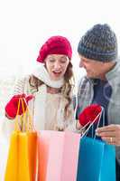 Happy couple in warm clothing opening shopping bags