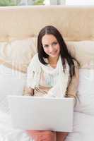 Pretty brunette using laptop on bed