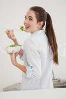 Pretty brunette eating bowl of salad