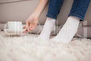 Woman picking up cup and saucer