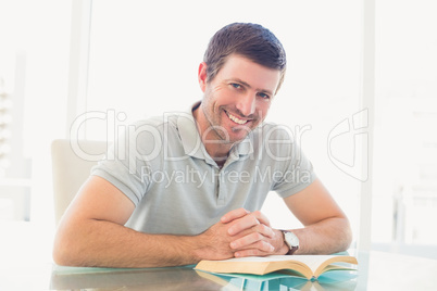 Casual businessman sitting at desk reading a book