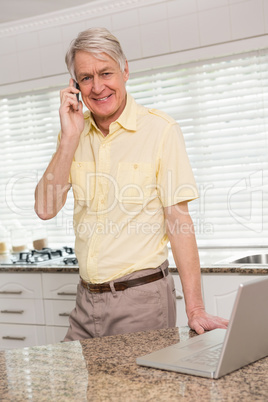 Senior man using his laptop on the phone