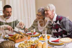 Man carving chicken during christmas dinner