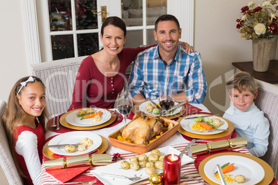 Smiling family looking at camera during christmas dinner