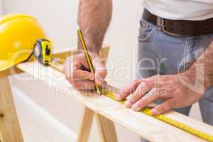 Casual man measuring plank of wood