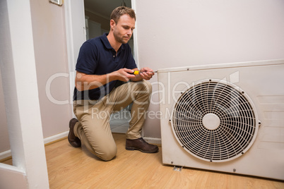 Focused handyman fixing air conditioning