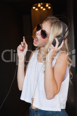 Pretty blonde in sunglasses listening to music and singing