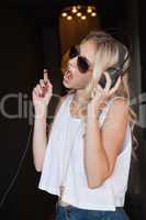 Pretty blonde in sunglasses listening to music and singing