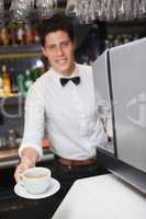 Barista offering cup of coffee smiling at camera